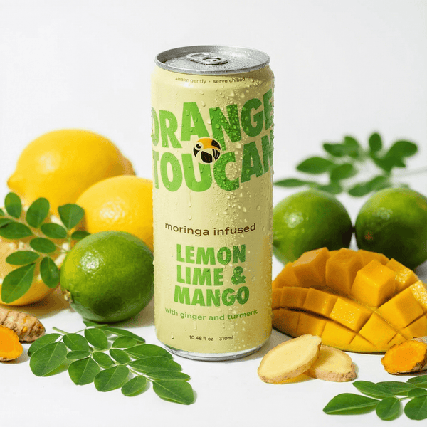 Orang Toucan lemon lime mango drink can with moringa, lemons, limes, ginger, and tumeric on a white background
