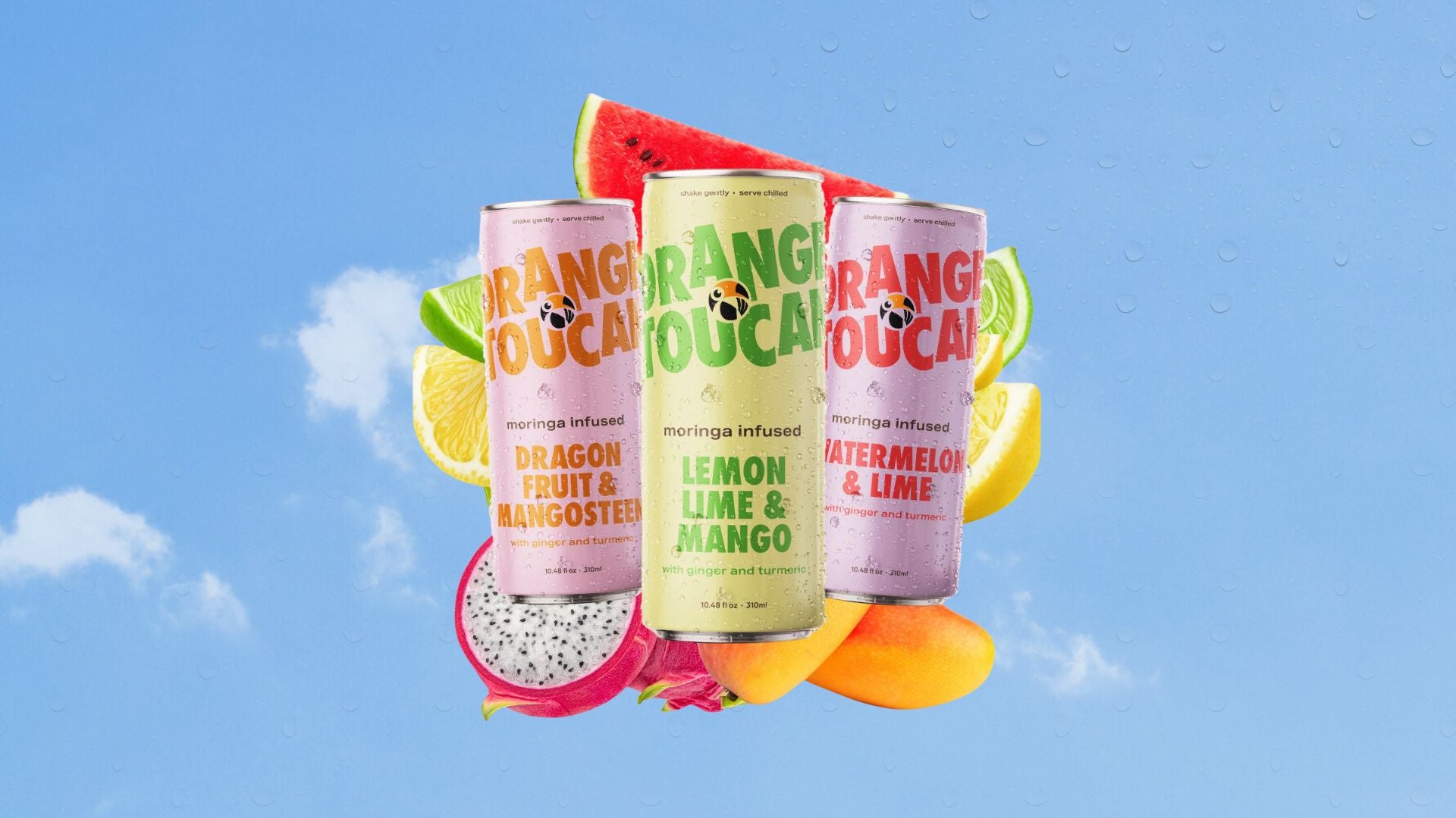 Three cans of moringa infused Orange Toucan drinks, containing ginger and turmeric, with fruit slices against a blue sky background
