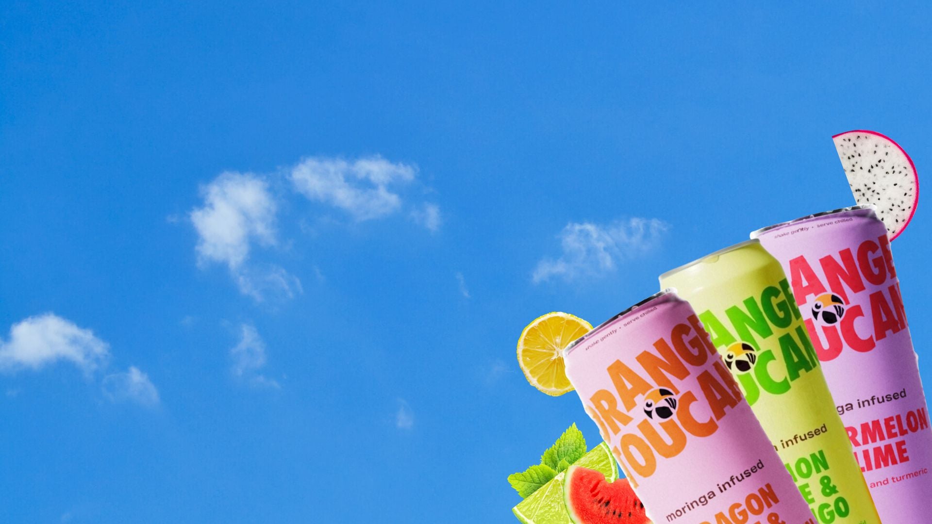 Three colourful Orange Toucan drinks with fruit slices against a blue sky