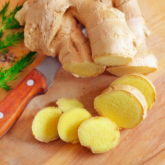 Sliced ginger on a wooden cutting board with a knife